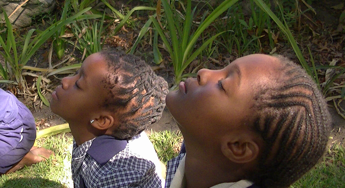 Children sitting focusing on sensing the air against their faces.
